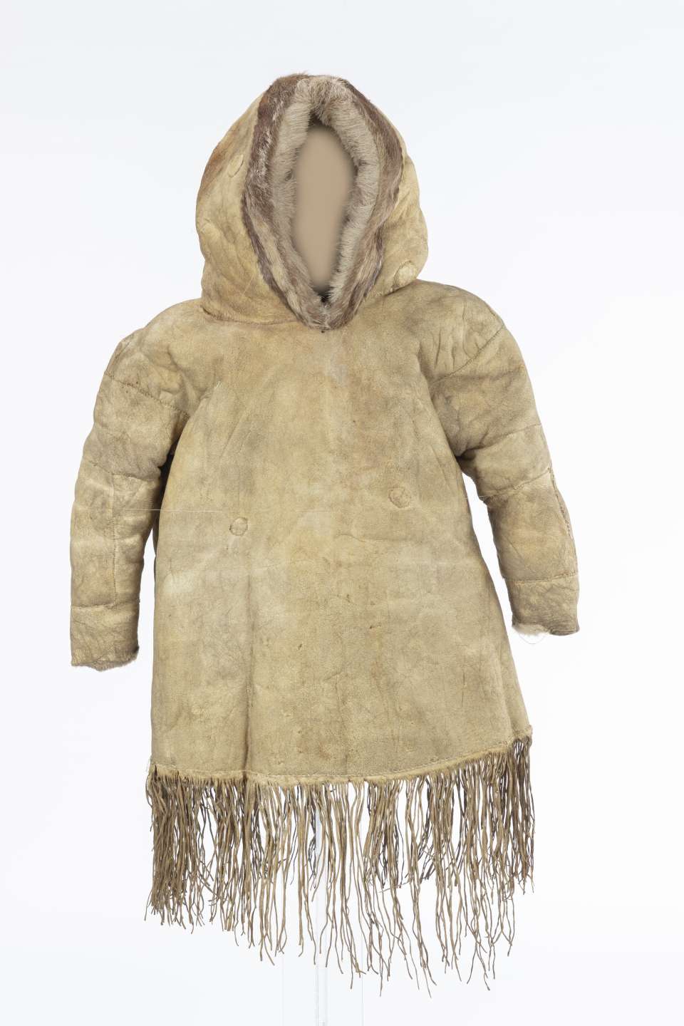 Veste en cuir beige, vue de face, avec le capuchon relev&eacute;. Le capuchon est bord&eacute; de fourrure brune. Des franges ornent le bas de la veste.