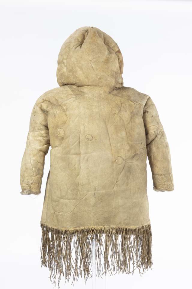 Veste en cuir beige, vue de derri&egrave;re, avec le capuchon relev&eacute;. Des franges ornent le bas de la veste.