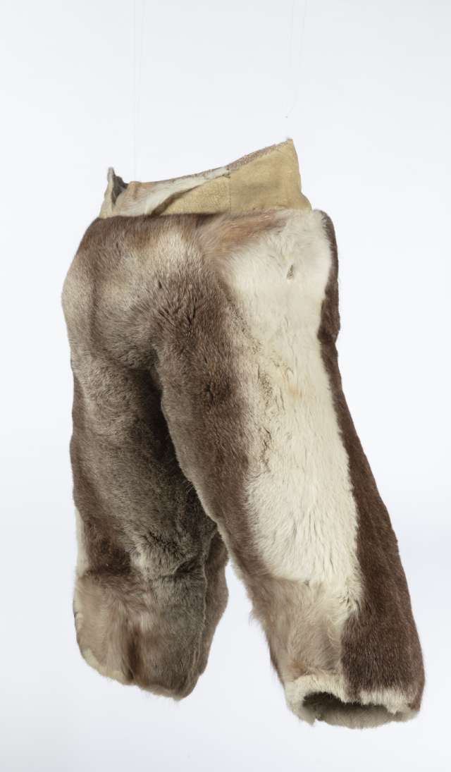 Pantalon de fourrure, vu de profil, soulignant la forme large et la disposition des rayures verticales brunes et blanches. La bande de cuir retourn&eacute; &agrave; la taille est plus basse &agrave; l&rsquo;arri&egrave;re qu&rsquo;&agrave; l&rsquo;avant.