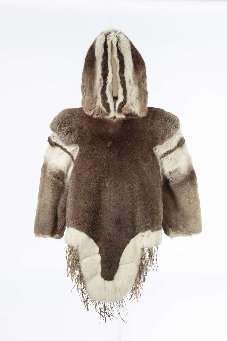 Manteau en fourrure, vu de face, orn&eacute; de bandes verticales de fourrure claire et fonc&eacute;e sur les &eacute;paules et sur le capuchon relev&eacute;. Le pan avant du manteau, bord&eacute; de fourrure blanche, se termine par une pointe arrondie, prolong&eacute;e de franges.