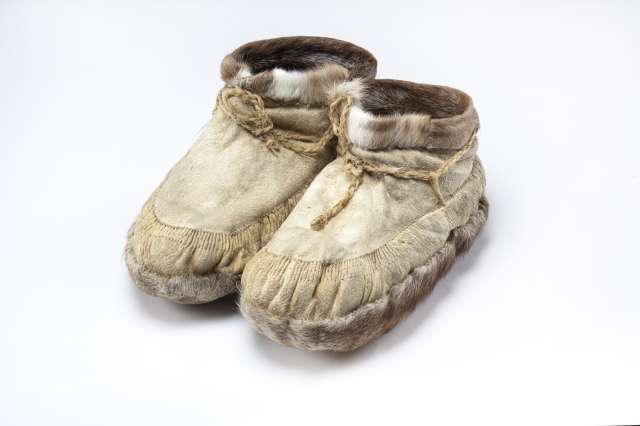 Une paire de bottillons, en cuir beige, orn&eacute;s de fourrure brune et blanche autour des chevilles, de fourrure brune sous la semelle et de cordons de serrage.