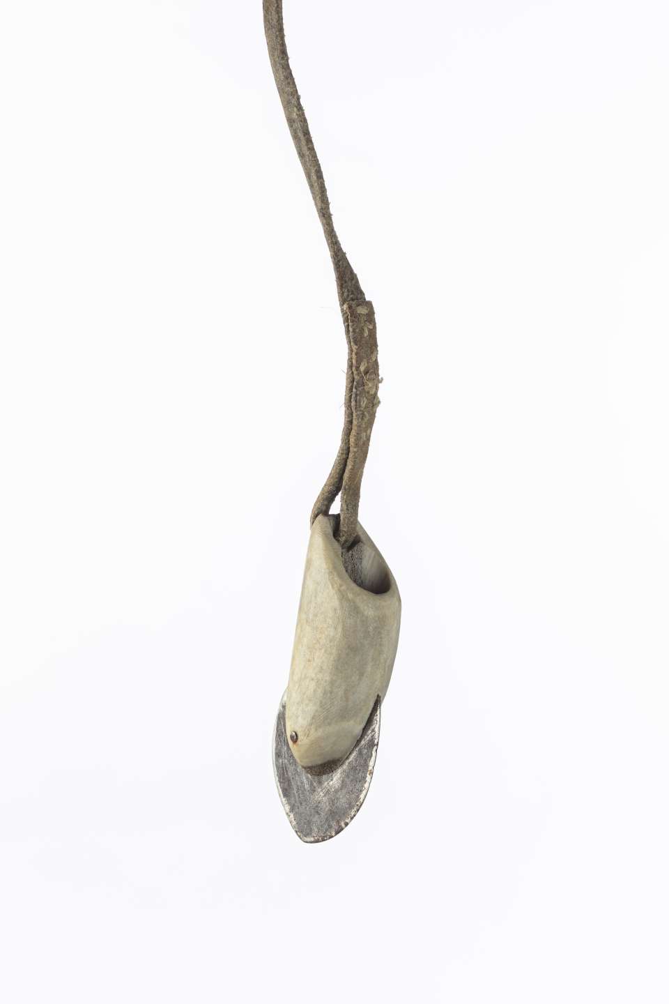 Vue rapproch&eacute;e d&rsquo;une t&ecirc;te de harpon suspendue, montrant une lame en m&eacute;tal ins&eacute;r&eacute;e dans un manche d&rsquo;andouiller attach&eacute; &agrave; un cordon en cuir. Les points de couture sur le cordon sont apparents.