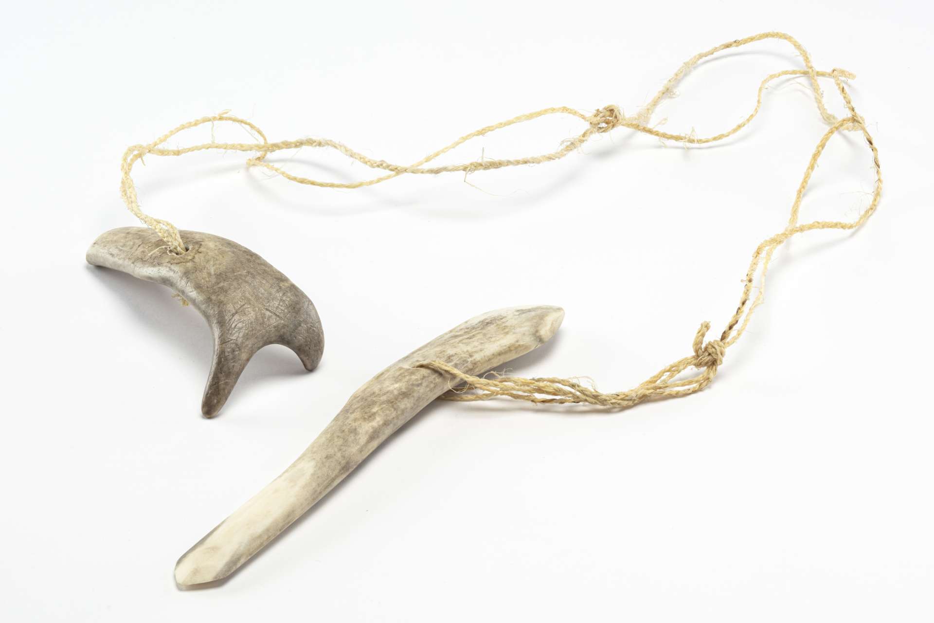 Deux outils en andouiller reli&eacute;s par une corde. L&rsquo;un des outils a une forme en Y, tandis que l&rsquo;autre est droit et l&eacute;g&egrave;rement effil&eacute; &agrave; son extr&eacute;mit&eacute;. La corde est nou&eacute;e en plusieurs endroits, reliant les deux outils.