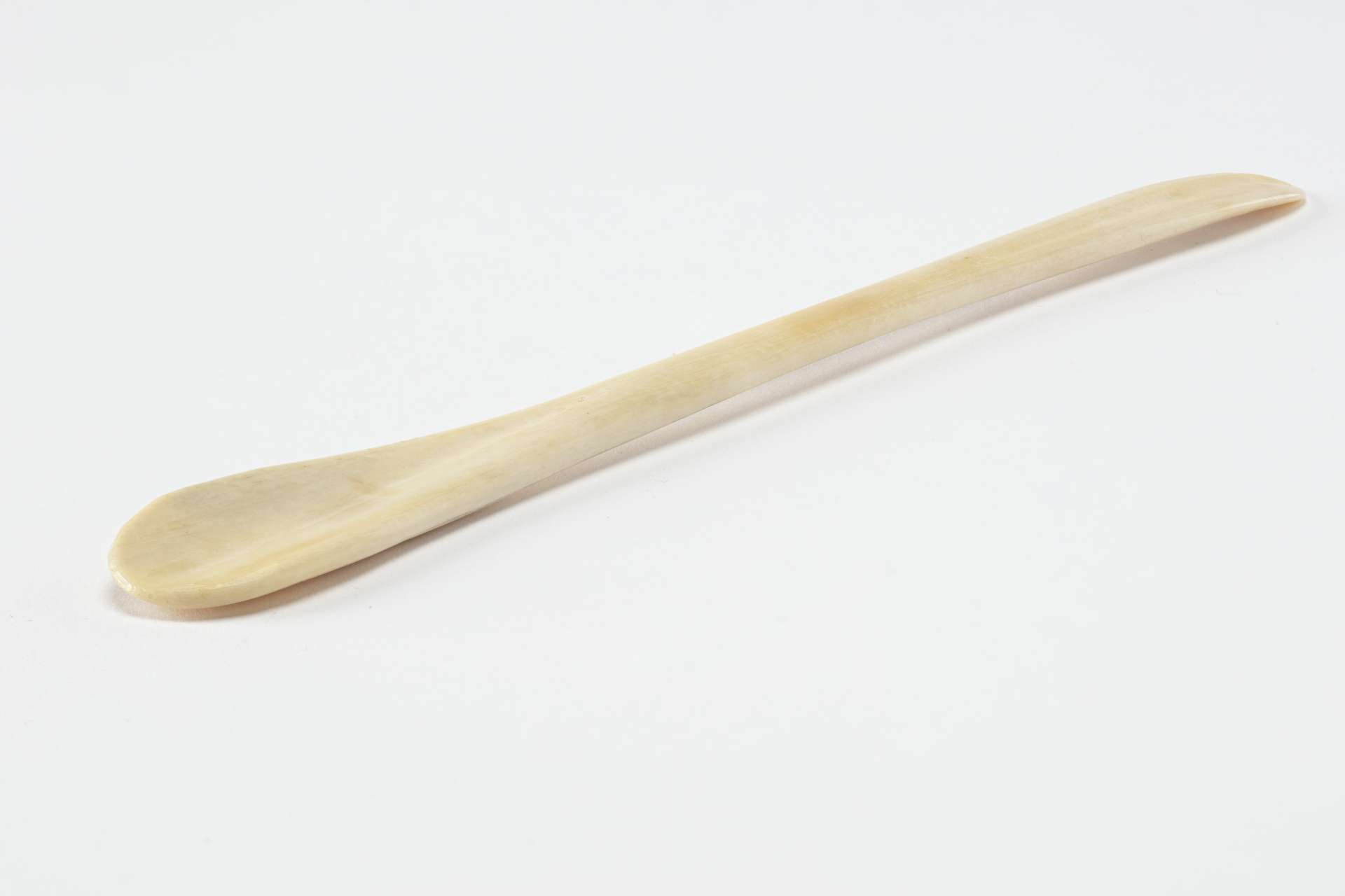 Cuill&egrave;re allong&eacute;e et finement polie en os, avec une extr&eacute;mit&eacute; large et arrondie et une autre plus fine et &eacute;troite. La surface de l&rsquo;ustensile est lisse et l&eacute;g&egrave;rement courb&eacute;e.